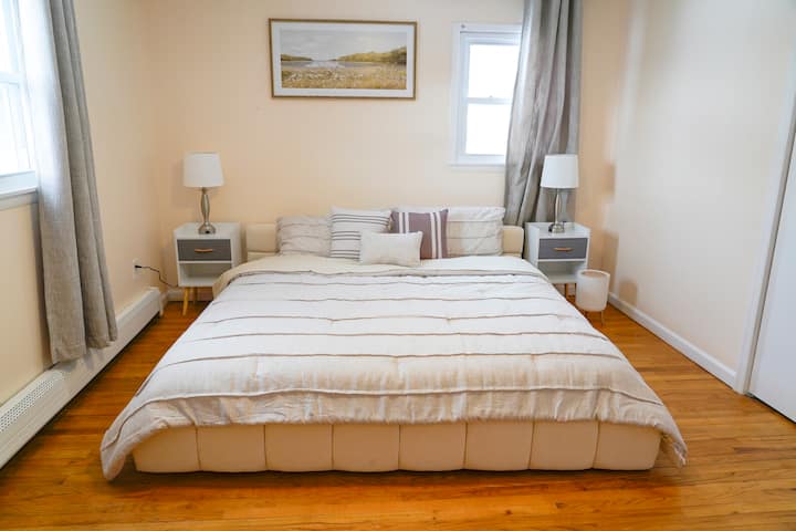 חדר שינה ראשי מרווח עם מיטת קינג סייז נוחה, מצעים רכים ושפע של אור טבעי.