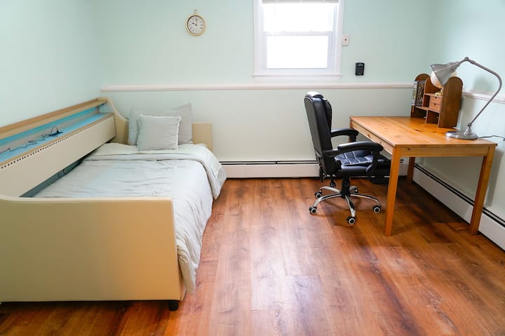 חדר אורחים בקומה התחתונה עם פינת עבודה ייעודית ומיטת יחיד נפתחת.
הנכס המואר והפונקציונלי הזה מציע מקום נוח לשינה או לעבודה, עם שולחן עבודה, כיסא משרדי עם גלגלים ואור טבעי מהחלון.