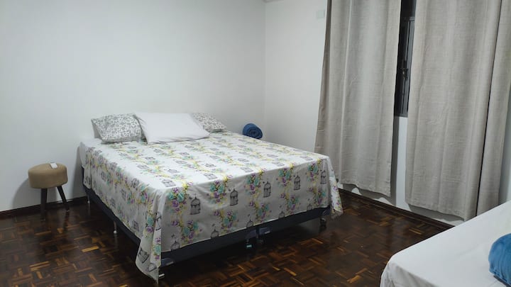 Dormitorio grande con cama queen, 1 cama individual, 1 cuna, aire acondicionado y persiana opaca. Ideal para parejas que desean tener al bebé cerca y, al mismo tiempo, disponer de espacio para moverse por la habitación.