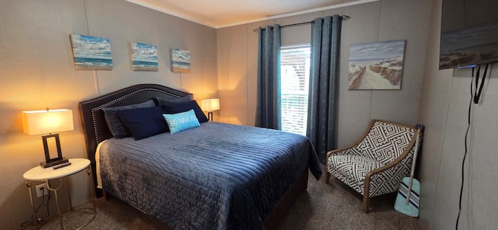 El dormitorio de invitados tiene una cama tamaño queen, un sillón de lectura y un televisor inteligente.