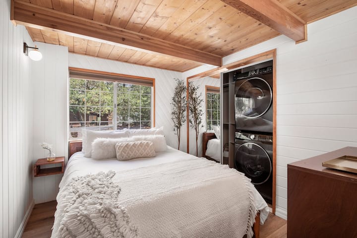 Cozy queen bedroom featuring a stackable washer and dryer in the closet.
