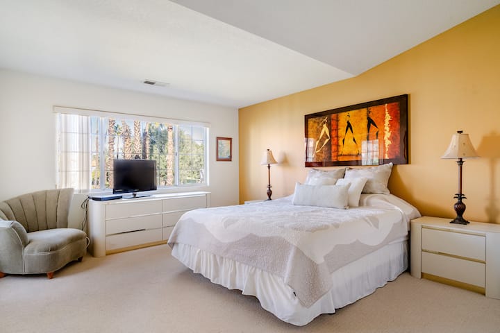 The primary bedroom with connected ensuite bathroom features a king size bed, TV, and plenty of clothing storage. There is also direct access to the unit's private outdoor balcony.