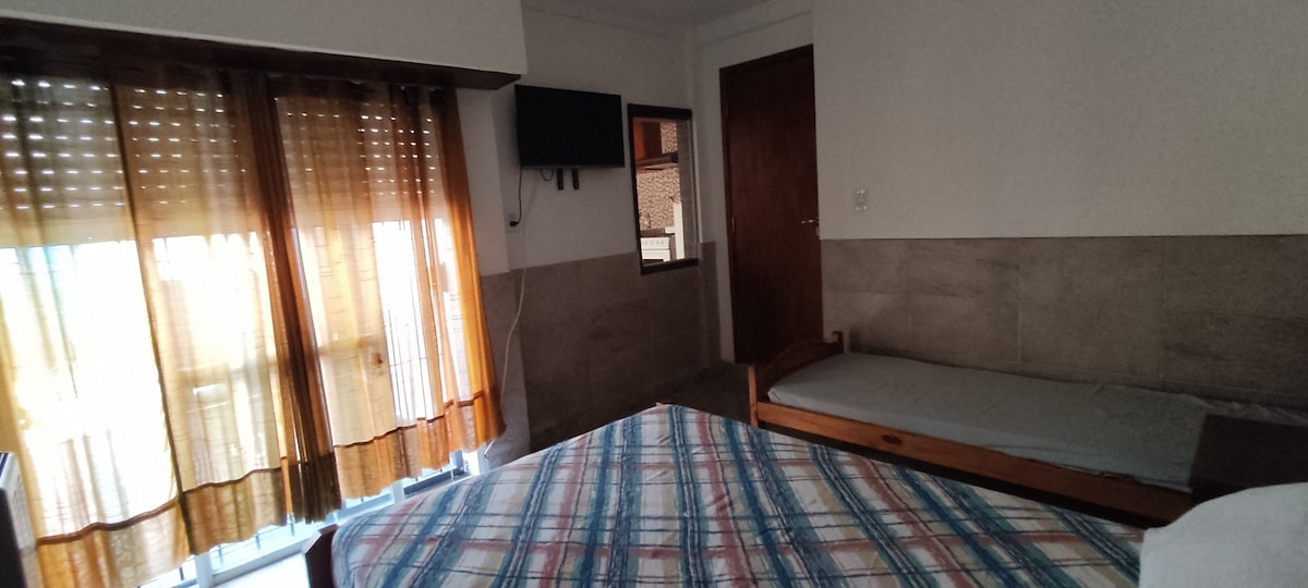 ห้องพักพร้อมทีวี เตียงคู่ 1 เตียงและเตียงเดี่ยว 1 เตียง มีเตียงเดี่ยวอีกเตียงในห้องอาหาร