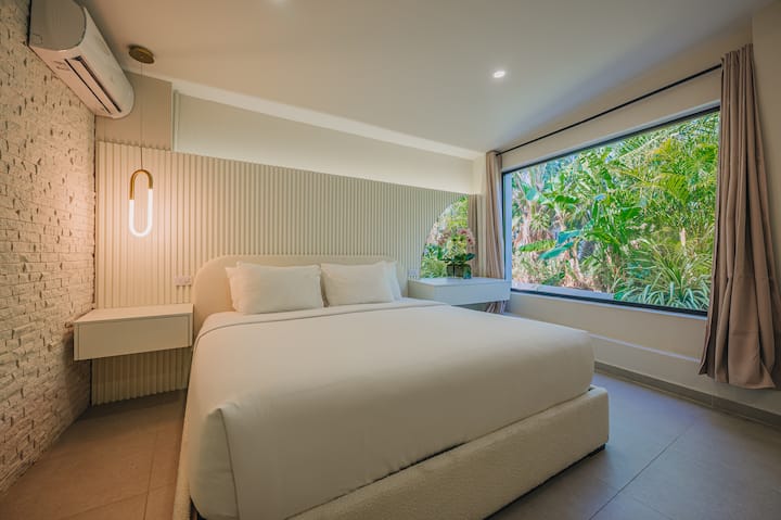 Dormitorio 10: una habitación tranquila y luminosa con una cama tamaño king y exuberantes vistas al jardín, perfecta para relajarse y disfrutar de una noche de sueño reparador.