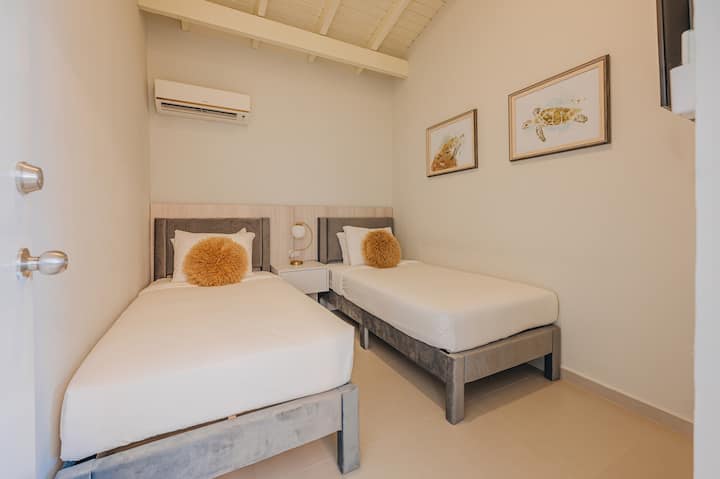 Dormitorio 6: una habitación sencilla y cómoda con dos camas individuales, sábanas frescas y una sensación tranquila y acogedora, ideal para compartir y descansar bien.