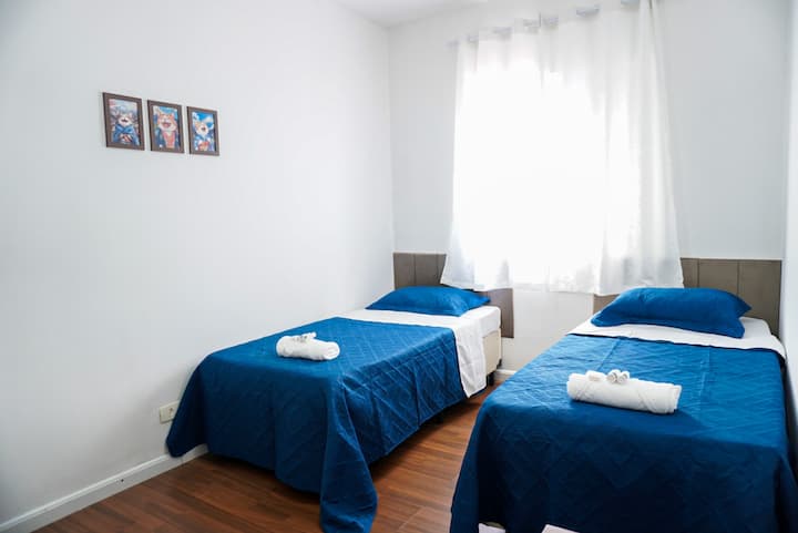 El dormitorio tiene un ventilador de techo, ropa de cama, almohadas y un armario para guardar la ropa.