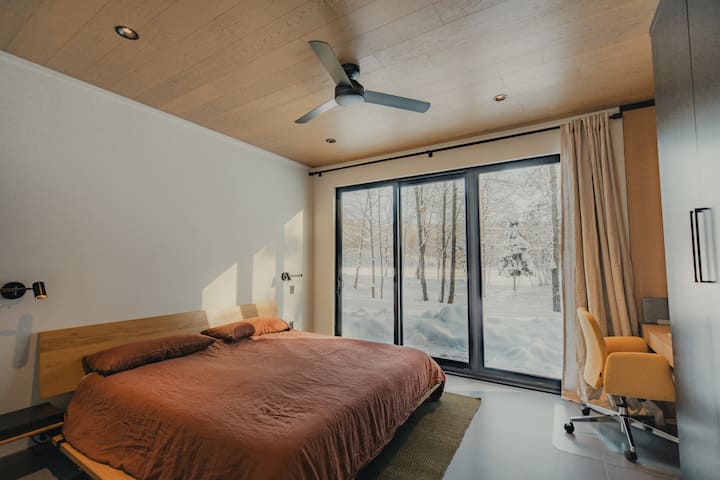Este es el dormitorio principal con una cama tamaño king y grandes ventanales con vistas al bosque y al lago. Es luminosa durante el día, silenciosa por la noche y está diseñada para un sueño profundo y confortable.
