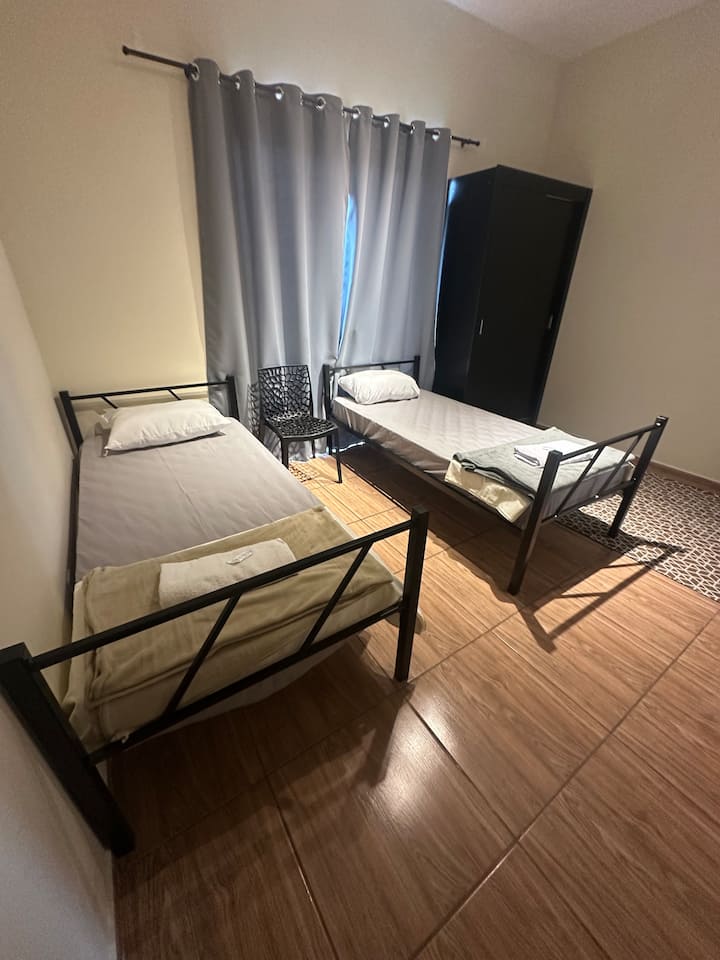 Dhomë e rehatshme dhe funksionale, ideale për të pushuar pas punës ose udhëtimit. Atmosferë e rehatshme me krevate komode, një gardërobë të madhe, perde errësuese dhe dekor modern. Hapësirë e pastër dhe e qetë e përgatitur për qëndrimin tënd në Araquari.