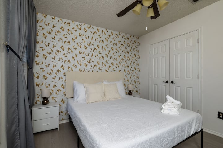 Bright bedroom with a stylish butterfly accent wall and queen-size bed.
