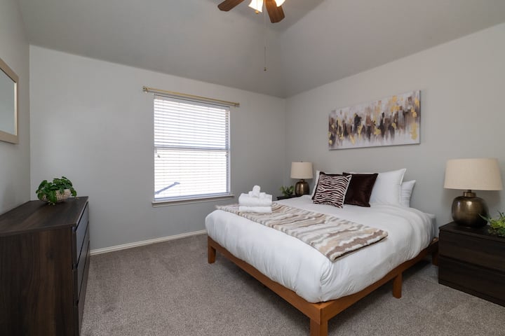 Modern second bedroom with a queen bed and stylish neutral decor.