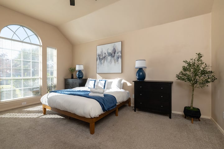 Airy master suite with a king bed and vaulted ceilings.