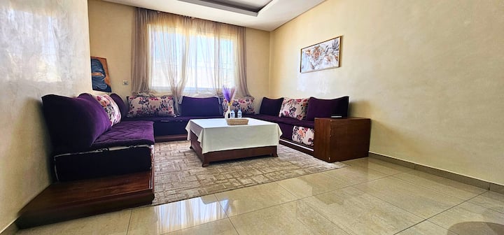 Grand salon lumineux avec banquettes confortables et table basse centrale. Un espace chaleureux et spacieux, parfait pour se détendre et partager des moments conviviaux en famille ou entre amis.