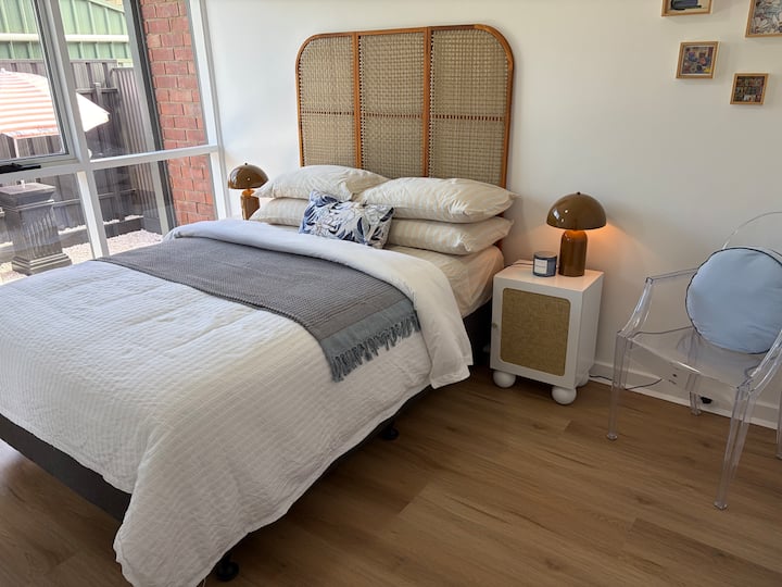 Cómodo dormitorio doble con colchón y ropa de cama de calidad, ventilador de techo y bata incorporada con espejo.
