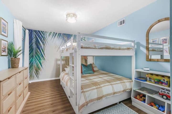 Un dormitorio elegante con literas tamaño queen y una cama nido extraíble para la máxima comodidad.  