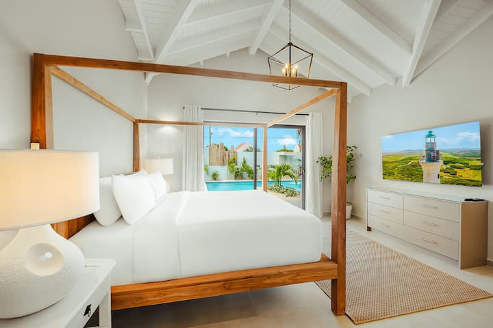 Master bedroom 1 overlooking the pool with ensuite, canopy bed, large closet, dresser and 65" TV