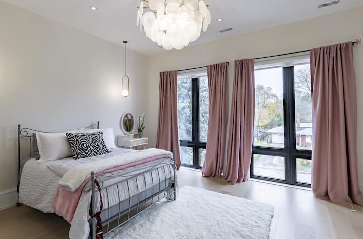 Dormitorio luminoso con ventanas del piso al techo y detalles en rosa suave