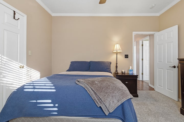 Gastenslaapkamer met comfortabel queensize bed en nachtkastje.