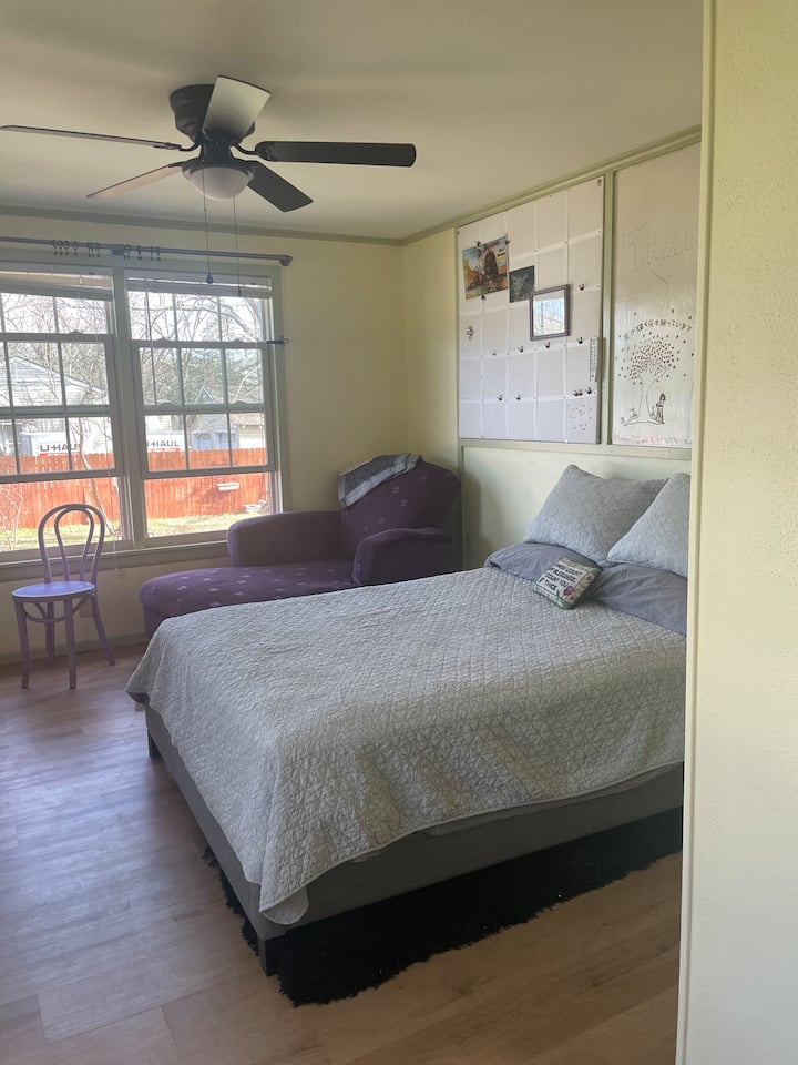 Deze lichte slaapkamer heeft een eigen kleine veranda, een eigen ingang vanaf de zijstraat en kijkt uit over de achtertuin. Full size bed met een nachtkastje en lamp aan elke kant. Voel je vrij om je eigen kunstwerk toe te voegen aan het whiteboard.