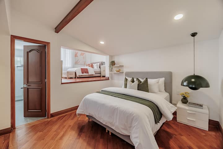 Suite familiar n.º 4: cama principal tamaño queen con Smart TV, caja fuerte digital, aire acondicionado independiente y baño privado en la habitación. La suite también cuenta con una segunda zona de descanso elevada con una cama de tamaño completo y una cama nido extraíble.
