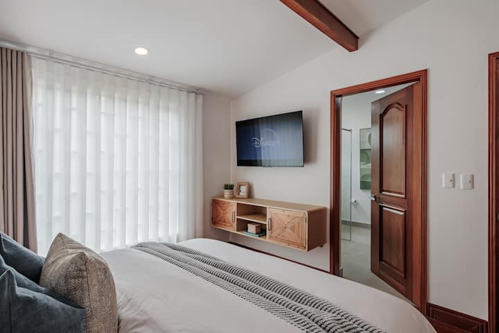 Suite privada n.º 2: elegante habitación con cama tamaño queen, Smart TV, aire acondicionado y acceso directo a un baño privado en la habitación.
