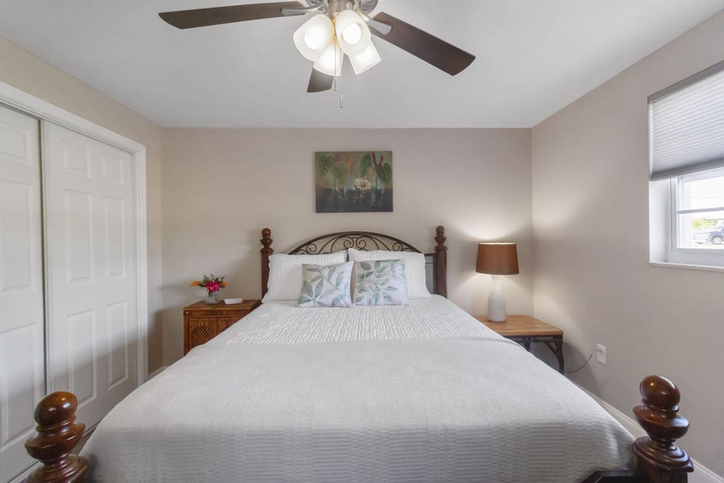 Dormitorio queen para huéspedes, armario con puerta corredera doble con vestidor y TV.  Persianas de panal para privacidad.  Hay almohadas adicionales, y la plancha y la tabla de planchar están en el armario.  