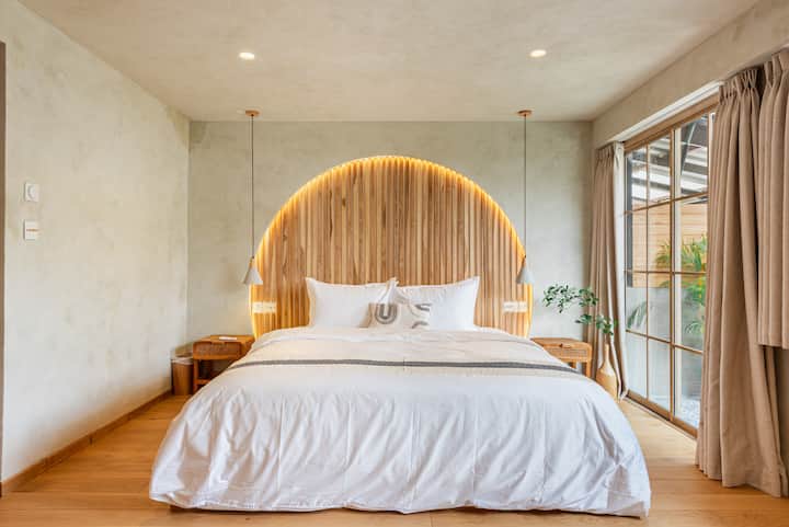 Chumba cha pili cha kulala chenye utulivu kilicho na kitanda aina ya king, ubao wa mbao wa kichwa cha kitanda na mwanga laini wa kimazingira, kinafaa kwa ajili ya kupumzika katika sehemu tulivu, iliyobuniwa kwa umakini.