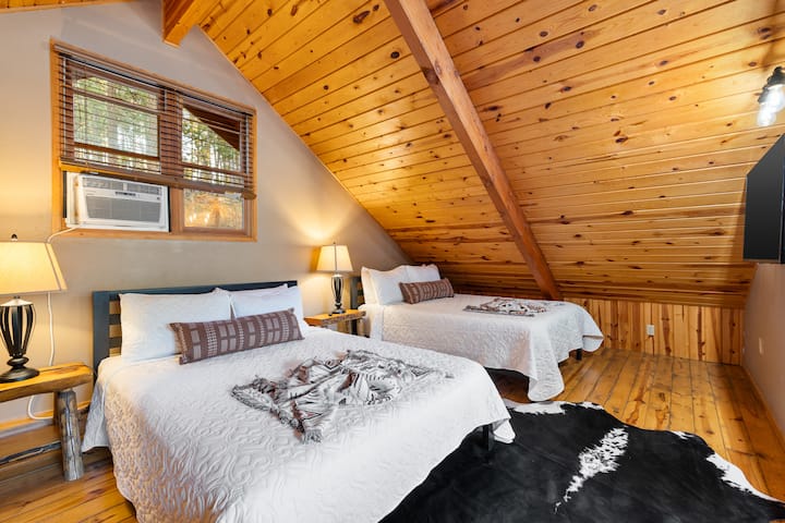 Ruime slaapkamer op zolder met twee bedden, warme houten plafonds en gezinsvriendelijke ruimte in onze Hillside Country Cabin.