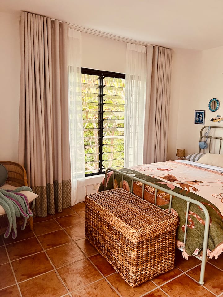 Esta hermosa segunda recámara cuenta con un armario con mucho espacio, un balcón Juliette, hermosas vistas al jardín, aire acondicionado y su propio baño privado.