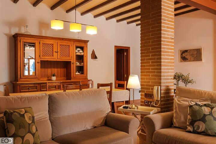 Salón con sofá, aparador rústico y columna de ladrillo visto: mucho encanto mediterráneo.