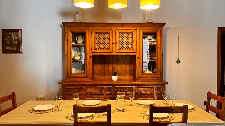 Comedor 1 con mesa puesta para varios comensales y vitrina: listo para disfrutar en compañía.