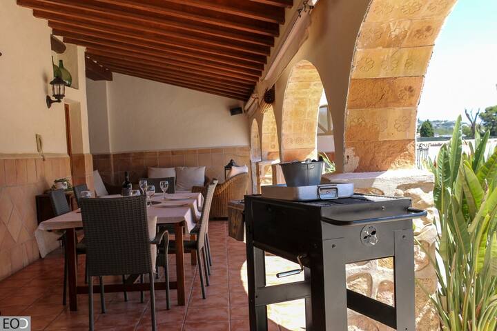 Comedor exterior con mesa vestida y barbacoa junto a los arcos: comidas al aire libre en compañía.