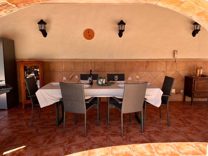 Comedor 3 con mesa amplia vestida y barbacoa al fondo: pensado para reuniones numerosas.