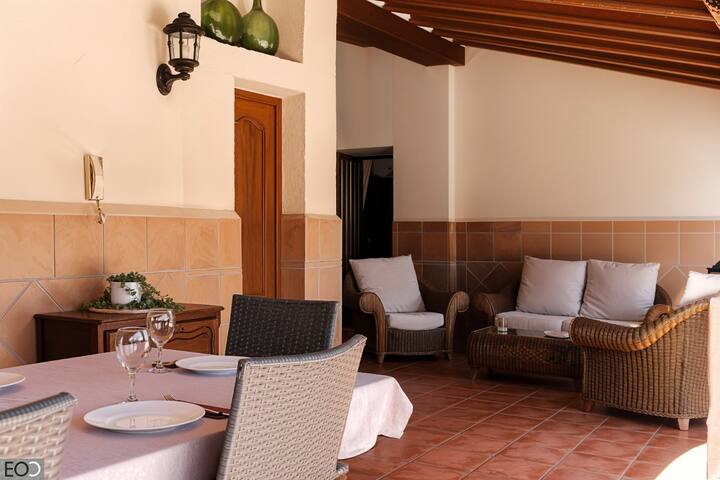 Terraza cubierta con sofás de mimbre y mesa: perfecta para sobremesas al aire libre.
