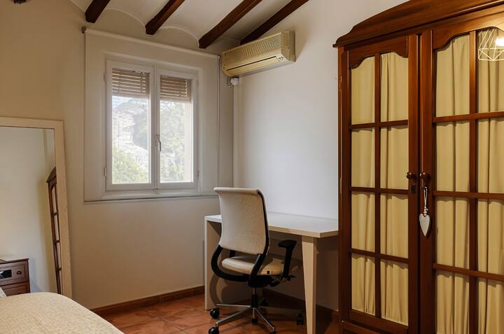 Rincón de escritorio junto a la ventana y el armario: práctico para trabajar o leer.