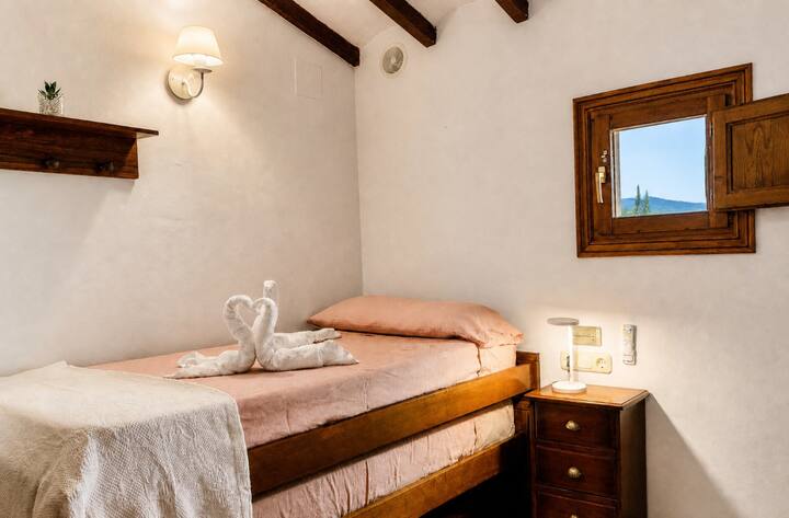 Dormitorio 4 con cama individual, mesilla y espejo bajo las vigas: acogedor y con luz natural.