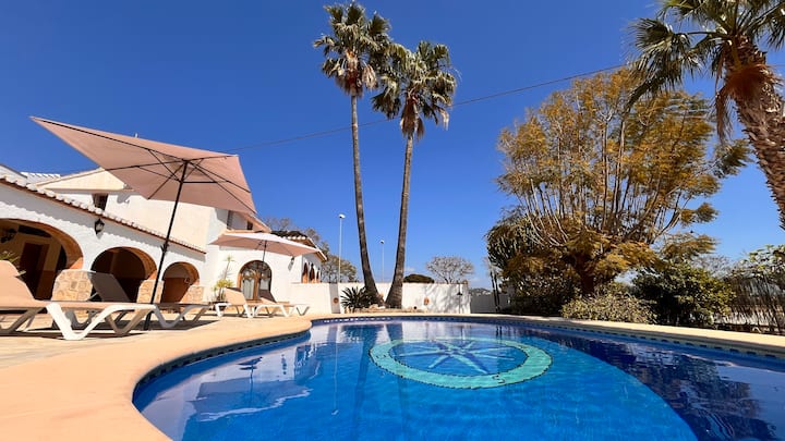 Piscina privada con palmeras y sombrilla: un oasis para refrescarse en verano.