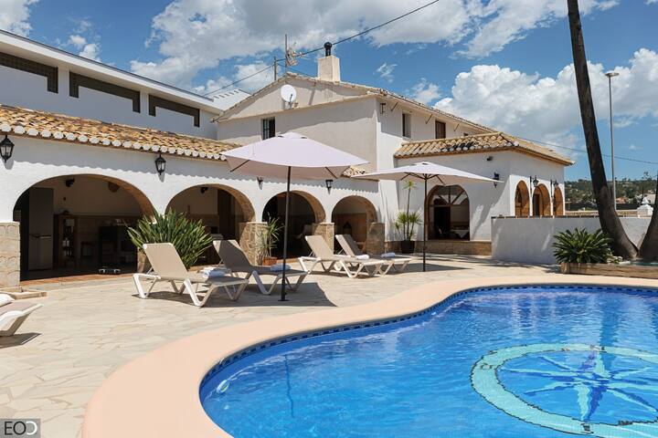 Piscina privada con tumbonas y la villa al fondo: gran zona exterior soleada.