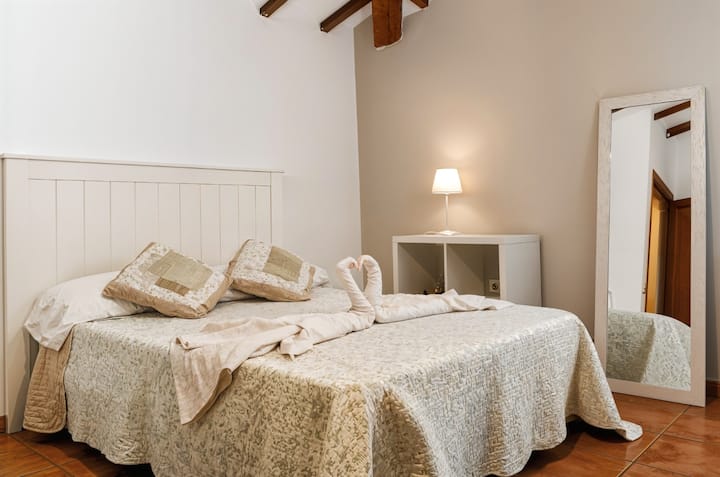 Dormitorio 1 con cama de matrimonio, espejo y detalles en blanco: luminoso y acogedor.
