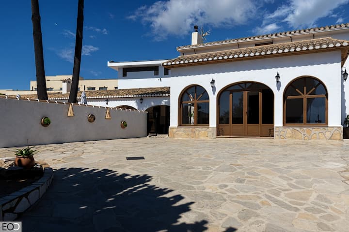 Fachada de la villa con arcos y gran patio empedrado: casa amplia y con mucho encanto mediterráneo.