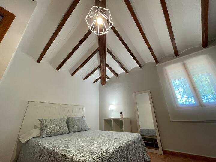 Dormitorio 1 abuhardillado con lámpara de diseño y claraboya: luz natural y encanto.