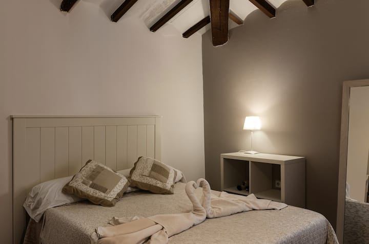 Cama de matrimonio del dormitorio 1 con cabecero de madera y mesilla: descanso asegurado.