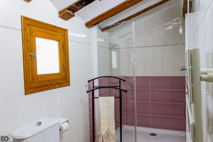 Baño completo 1 con ducha, inodoro y espejo de madera: funcional y con toques rústicos.