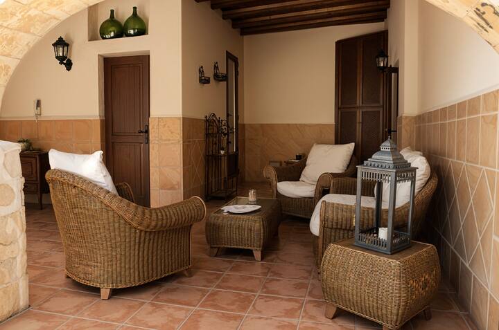 Zona chill-out de la terraza con butacas de mimbre y farol: ambiente acogedor a la sombra.