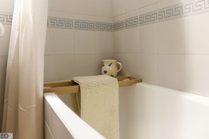 Bañera con cortina y bandeja de madera en el baño 2: listo para un baño relajante.