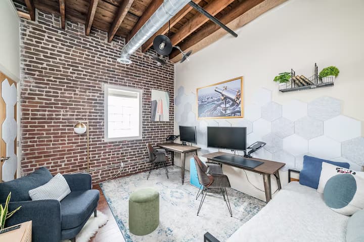 פינת עבודה ייעודית עם שולחן, פינת ישיבה וקירות לבנים חשופים.