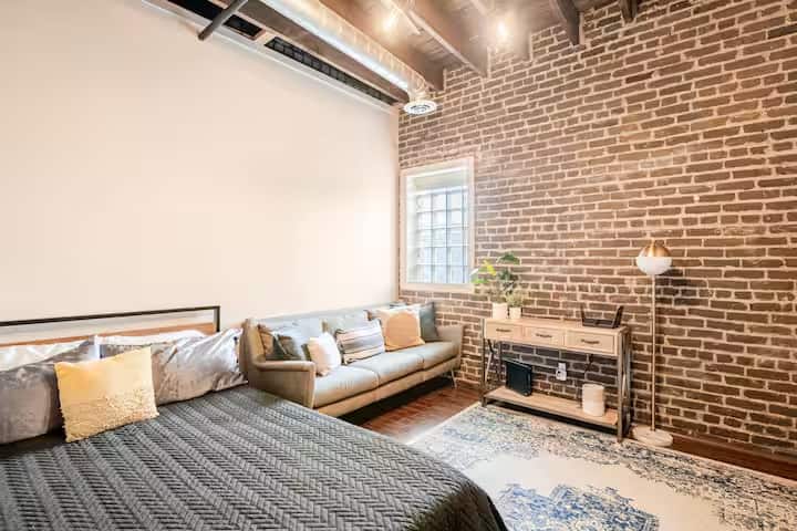 חדר שינה מרווח עם לבנים חשופות ופינת ישיבה נעימה.