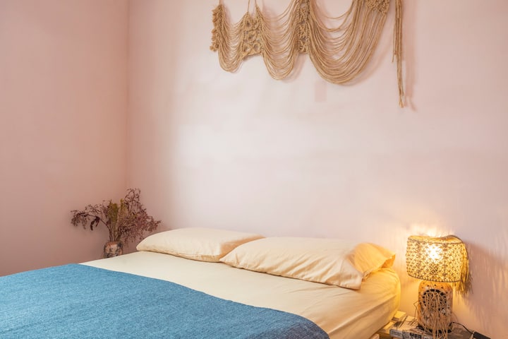 Cómoda cama doble con iluminación acogedora y decoración artesanal.