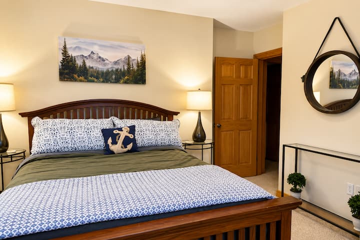Comfortable bedroom with soft bedding, warm lighting, and classic mountain-home décor provides a restful retreat for guests after a full day of North Conway sightseeing, hiking, skiing, or lake adventures.