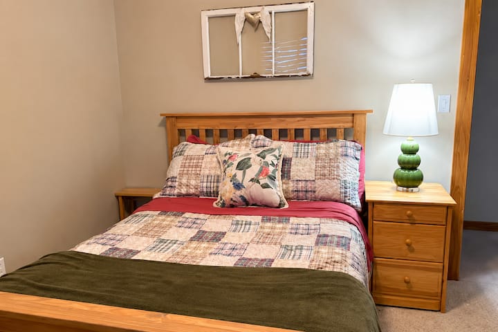 Inviting bedroom with colorful bedding, warm wood accents, and a comfortable bed creates a cheerful retreat for guests enjoying a Conway, New Hampshire vacation near lakes, mountains, and local attractions.