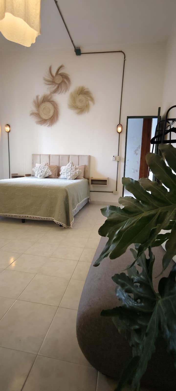 Habitación recién renovada con cama queen size, ropa de cama, elementos decorativos, love seat, área de trabajo y plantas naturales.